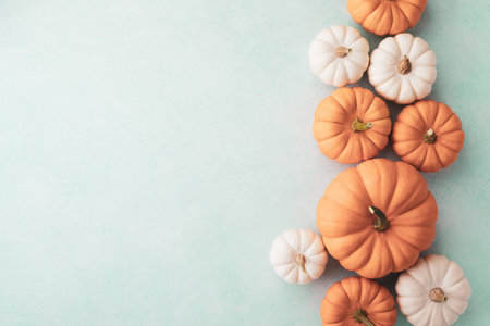 Border of small decorative pumpkins on blue background top view, flat lay. Autumn, Thanksgiving or Halloween minimalist greeting cardの写真素材