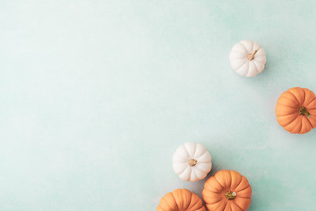 Small orange and white pumpkins on turquoise background top view, flat lay. Autumn, Thanksgiving or Halloween minimalist greeting cardの写真素材