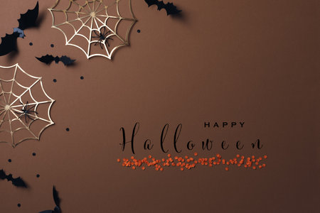 Halloween party decorations from bats, spider web and confetti top view. Minimal holiday greeting card with text insription happy halloween.の写真素材
