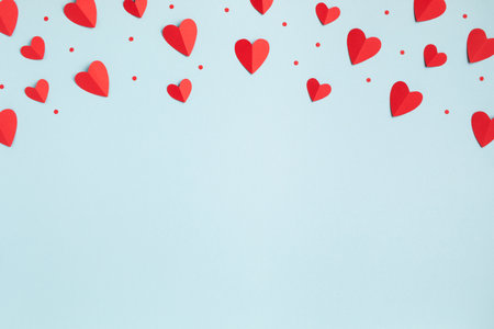 Valentine day festive greeting card with border of red hearts on pastel blue background top view. Flat lay style.の写真素材
