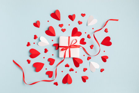 Valentine or Mother day festive composition with gift or present box and red hearts on pastel blue background top view. Flat lay greeting card.の写真素材