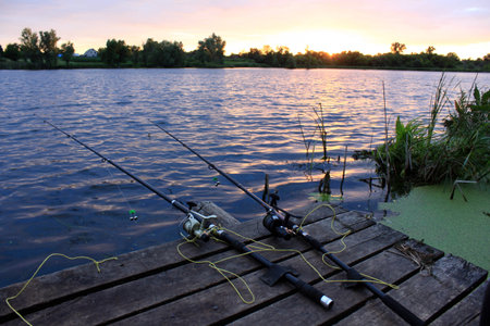 Fishing rods on the wooden bridge at sunset in autumn