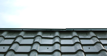 New green roof of house made of iron shingles against blue sky background closeup