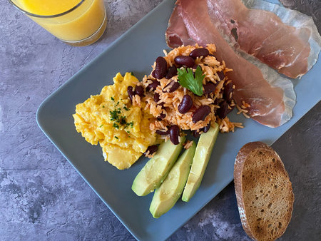 Healthy breakfast with scrambled eggs, avocado, beans and toasts