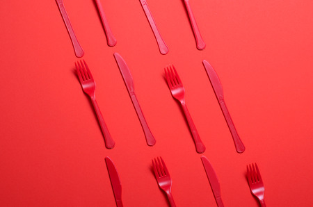 Red Forks and Knives on Bright Orange Background, Single Use Cutlery, Food Conceptの写真素材