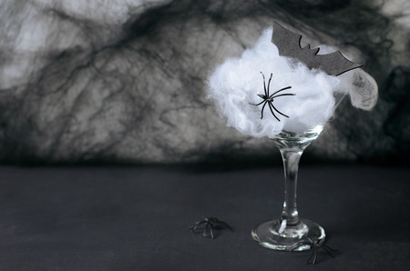 Halloween Cocktail Food Concept, Glass with Cobweb with Black Bat and Spider on Dark Background, Spooky Drinkの写真素材