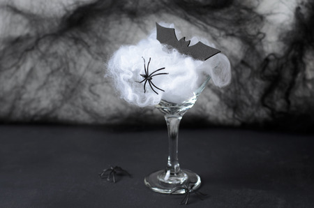 Halloween Cocktail Food Concept, Glass with Cobweb with Black Bat and Spider on Dark Background, Spooky Drinkの写真素材