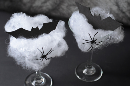 Halloween Cocktail Food Concept, Glass with Cobweb with Black Bat and Spider on Dark Background, Spooky Drinkの写真素材