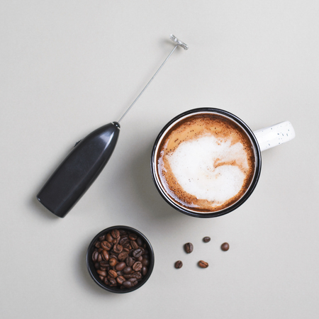 Cup of Coffee, Foam Maker and Coffee Beans on Bright Beige Background, Coffee with Cream Mugの写真素材