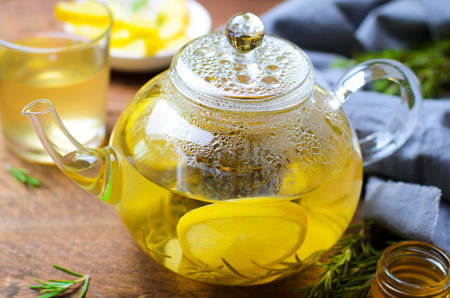 Healthy Ginger Tea with Lemon, Rosemary and Honey in Glass Teapot on Dark Wooden Backgroundの写真素材