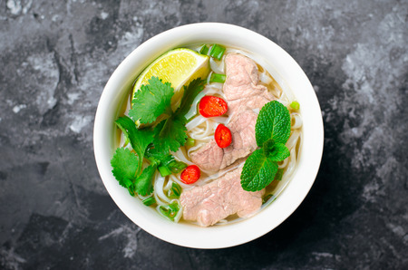 Traditional Vietnamese Soup Pho Bo with Rice Noodles, Beef and Herbs on Dark Background, Asian Cuisineの写真素材