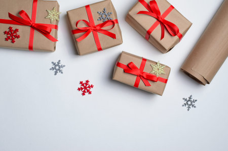 Winter Holidays Concept, Christmas Gifts Wrapped in Craft Paper with Red Ribbon and Snowflakes, Top...