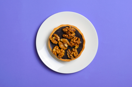 Walnut and Chocolate Tartlet, Dessert on White Plate on Purple Background, Top Viewの写真素材