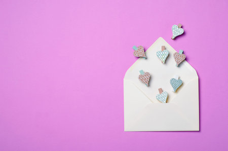 White Envelope on Purple Background and Heart Shaped Pins, Copy Space, Top View