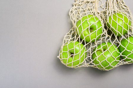 Apples in Mesh Bag, Reusable Eco Friendly Cotton Shopping Bag over Beige Backgroundの写真素材