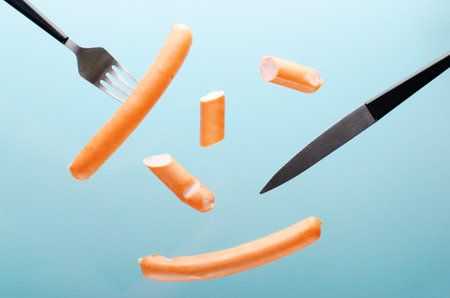 Sausages and Cutlery Levitating, Flying Food Concept, Light Blue background