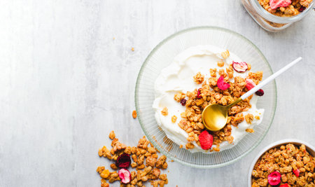 Granola with Yogurt in a Boal, Healthy Breakfast, Muesli with Dried Berries on Bright Backgroundの写真素材