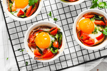 Baked Eggs with Bacon, Tomatoes, Spinach and Herbs on Bright Background, Healthy Rustic Breakfast or Snackの写真素材