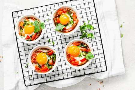 Baked Eggs with Bacon, Tomatoes, Spinach and Herbs on Bright Background, Healthy Rustic Breakfast or Snackの写真素材