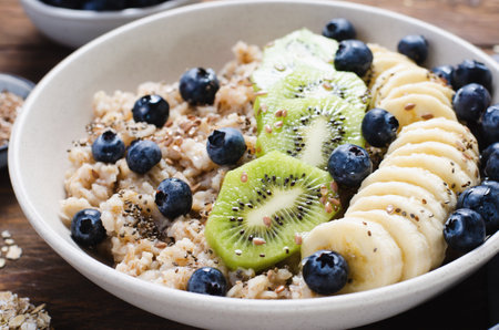 Oatmeal Bowl, Oat Porridge with Blueberry, Banana and Kiwi on Dark Rustic Background, Healthy Snack or Breakfastの写真素材