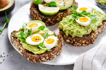 Avocado and Quail Egg Toasts, Healthy Snack or Breakfast on Bright Backgroundの写真素材