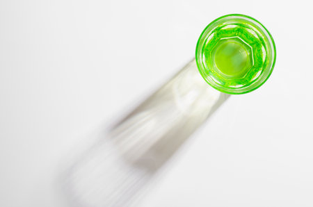 A Glass with Water and Sharp Shadows, Caustic Effect as Light Passes Through on Bright Backgroundの写真素材