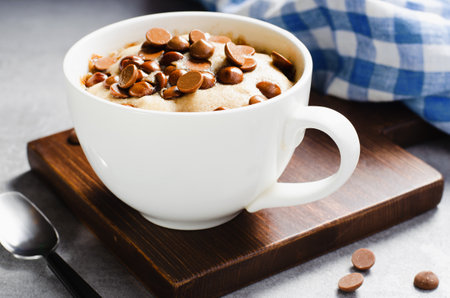 Peanut Butter and Chocolate Chips Mug Cake, Homemade Cake Cooked in the Microwave on Bright Backgroundの写真素材