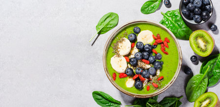 Healthy Green Smoothie in a Bowl with Banana, Blueberry, Goji, and Chia Seed Toppings, Detox, Vegan or Vegetarian Food on Bright Backgroundの写真素材