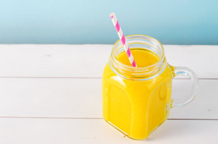 Orange Smoothie in a Jar, Vitamin Drink or Refreshing Cocktail on Bright Backgroundの写真素材
