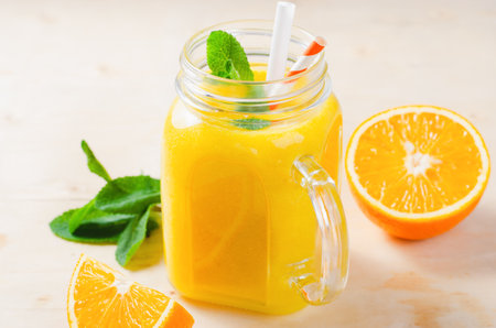 Orange Smoothie in a Jar, Vitamin Drink or Refreshing Cocktail on Bright Backgroundの写真素材