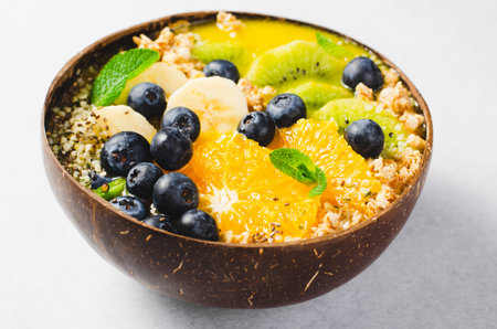 Smoothie Bowl with Orange, Kiwi, Blueberry, and Granola in a Coconut Bowl, Healthy Food, Vegan or...