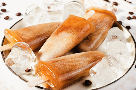 Coffee , Refreshing Ice Lollies with Coffee Beans and Ice on Bright Background, Tasty Frozen Treatの写真素材