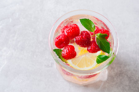 Refreshing Cold Cocktail or Mocktail with Berries and Lemon, Raspberry Lemonade on Bright Backgroundの写真素材