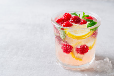 Refreshing Cold Cocktail or Mocktail with Berries and Lemon, Raspberry Lemonade on Bright Backgroundの写真素材