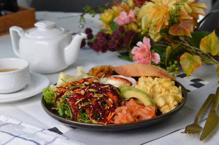 Healthy Breakfast with Salmon, Scrambled Eggs, Avocado, Vegetable Salad and Toppings on Bright Backgroundの写真素材