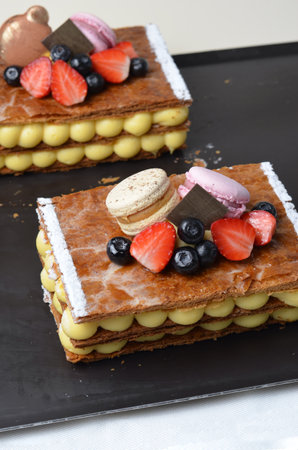 Traditional French dessert millefeuille with vanilla cream and fresh berries on Baking Tray Backgroundの写真素材