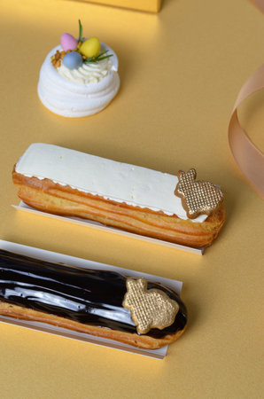 Delicious Eclairs on Golden Background, Chocolate and Vanilla Icing Eclairs with Easter Bunny Decor