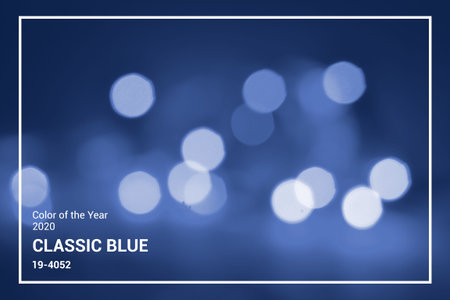 Lights on blue defocus background. Bokeh defocus disco effect. Holiday abstract background christmas lights garland. Winter festive glitter macro concept in trendy classic blue color of the year 2020の写真素材