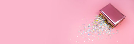 Confetti stars and rose gold purse on soft pink background. Banner with copy space. Holographic rainbow glitter in trendy pastel colors. Flat lay wallet composition. Business, finance, moneyの写真素材