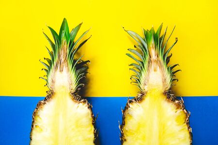 Modern flat lay pattern with two pineapple fruits half creative concept on blue and yellow background. Creative nature wallpaper. Summer tropical poster design. Simbol of couple, love, friendshipの写真素材