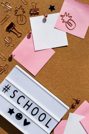 Board letter text back to school, office supplies on a cork desk flat lay. Pink, white note...