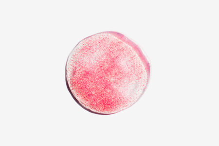 Pink transparent cosmetics drop on white background. Skincare scrub swatch with particles. Beauty...