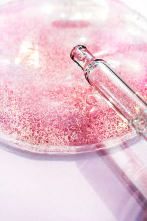 Drop of pink transparent facial serum with pipette . Skincare Liquid scrub gel macro swatch textureの写真素材