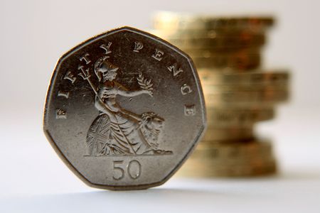 Fifty pence piece with stack of pound coins in backgroundの写真素材