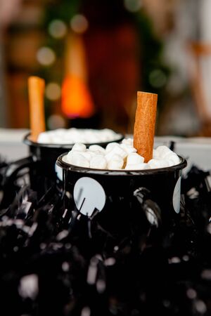 two black cups with hot cocoa and marshmallows with cinnamon sticks.の写真素材
