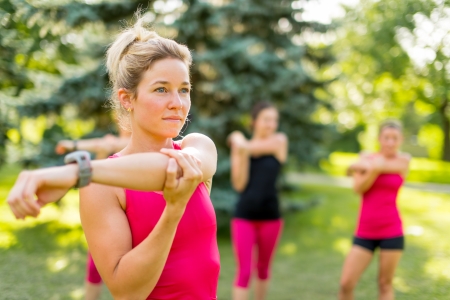 Portrait of a concentrated young woman streching her arm before jogging with friendsの写真素材