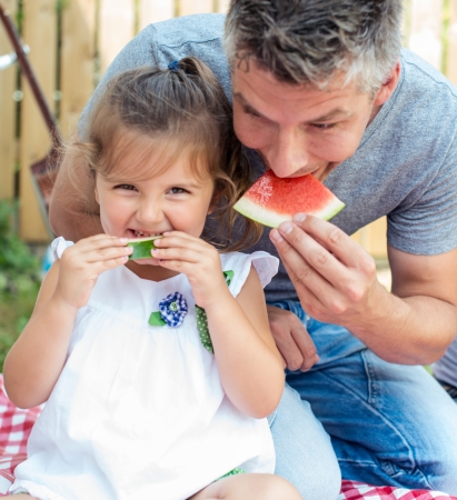 Father and little girl having watermelon on a picnicの写真素材