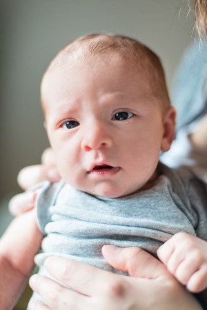Selective focus portrait of a serious baby boy looking at youの写真素材