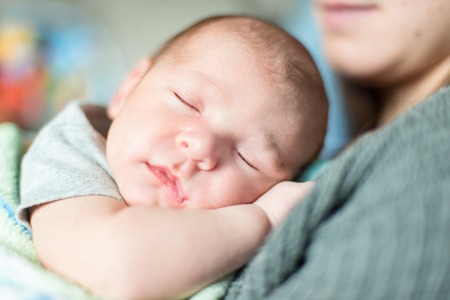 Selective focus portrait of a baby boy on his mother shoulderの写真素材