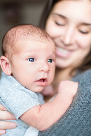 Selective focus portrait of a baby boy on his mother shoulder